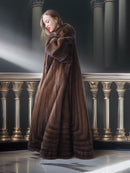 Woman wearing a long brown fur coat in an elegant interior setting.