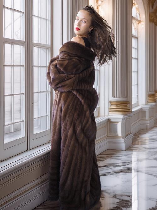 Woman wearing a fur coat in a luxurious room with marble floors and large windows.