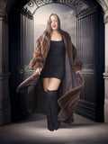 Woman wearing a long fur coat and black outfit in an ornate doorway.