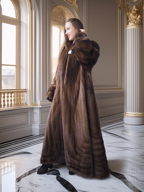 Woman wearing a long brown fur coat in an elegant interior setting.