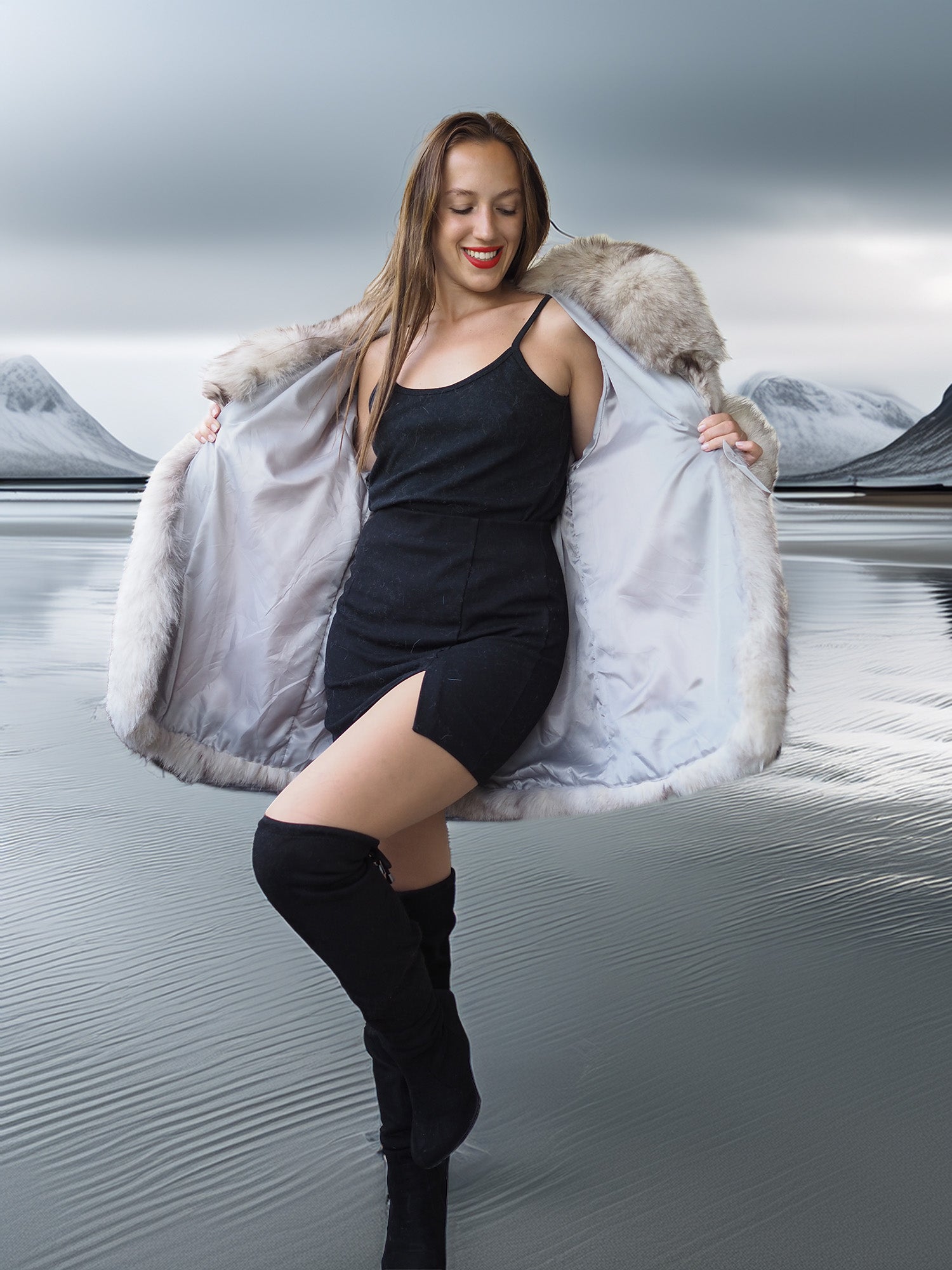Woman in a black dress and fur coat standing in a snowy landscape with mountains.