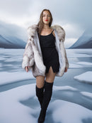 Woman in a fur coat and black dress standing in a snowy landscape