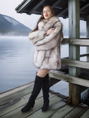 Woman in a fur coat standing on a wooden dock by a lake
