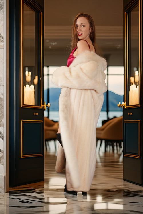 Woman in a white fur coat standing in a luxurious interior setting with candles and elegant decor.