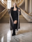 Woman in a long coat standing in an elegant interior setting with marble floors and stairs.