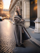 Woman in a long fur coat standing on a city street with classical architecture.