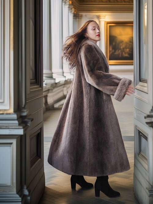 Woman in a long coat standing in an elegant interior setting