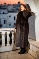 Woman in a fur coat standing on a balcony with a cityscape in the background