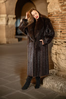 Woman wearing a fur coat standing in front of stone arches.
