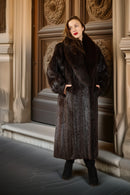 Woman wearing a fur coat standing in front of an ornate door.