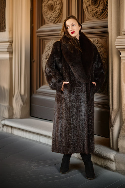 Woman wearing a fur coat standing in front of an ornate door.