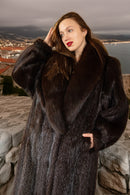 Woman wearing a fur coat standing outdoors with a scenic background
