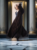 Woman in a long brown coat standing in a grand hallway with columns.