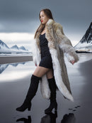 Woman in a fur coat standing in a snowy landscape with mountains.
