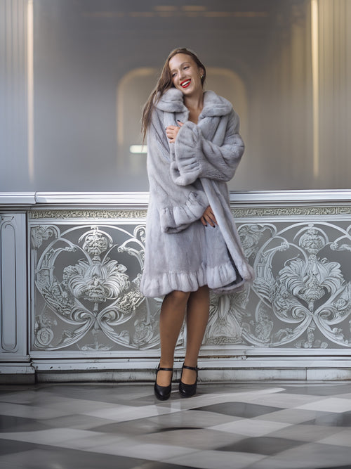 Woman in a gray fur coat standing in an elegant interior setting