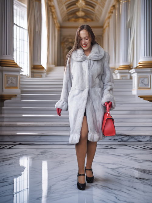 Woman in a long fur coat holding a red handbag in an elegant interior setting.