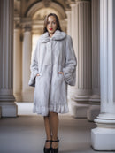 Woman wearing a light gray fur coat in an elegant interior setting