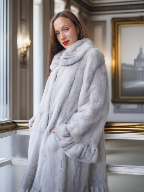 Woman wearing a light gray fur coat in an elegant interior setting