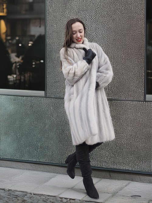 Model poses playfully in Sapphire Grey Mink Fur Coat S Petit Excellent against a modern textured wall, blending vintage and contemporary style.