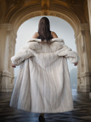 Person wearing a fur coat walking through an ornate hallway