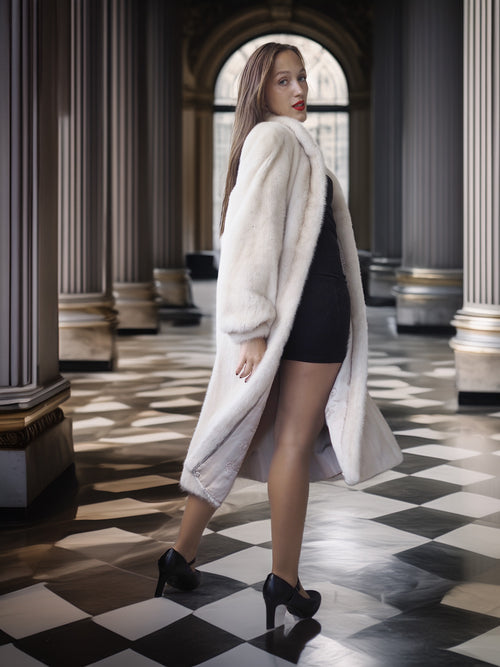 Woman in a white fur coat standing in an elegant interior setting with checkered floor.