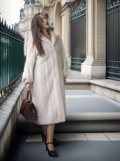 Woman in a long white fur coat standing on a city street.