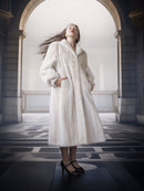 Woman wearing a white fur coat in an elegant interior setting