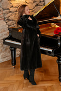 Woman in a black fur coat standing next to a grand piano with red flowers on a stone wall background