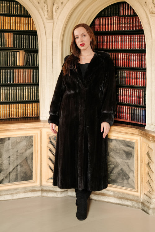 Woman wearing a black fur coat in a library setting