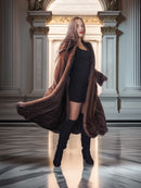 Woman in a long brown coat standing in an elegant interior setting