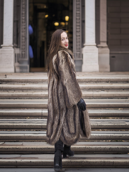 Back view of Canadian Raccoon Fur Coat in silver tips on stairs, highlighting full-length design and elegant winter outerwear.