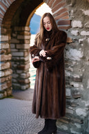 Rich brown mink coat with long sleeves, tie belt, and decorative clasp at the collar