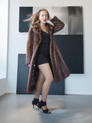 Woman wearing a long brown fur coat in a modern interior setting