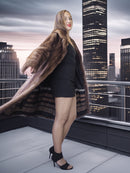 Woman in a fur coat standing on a rooftop with city skyline in the background