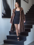 Woman in a long brown fur coat standing on a staircase