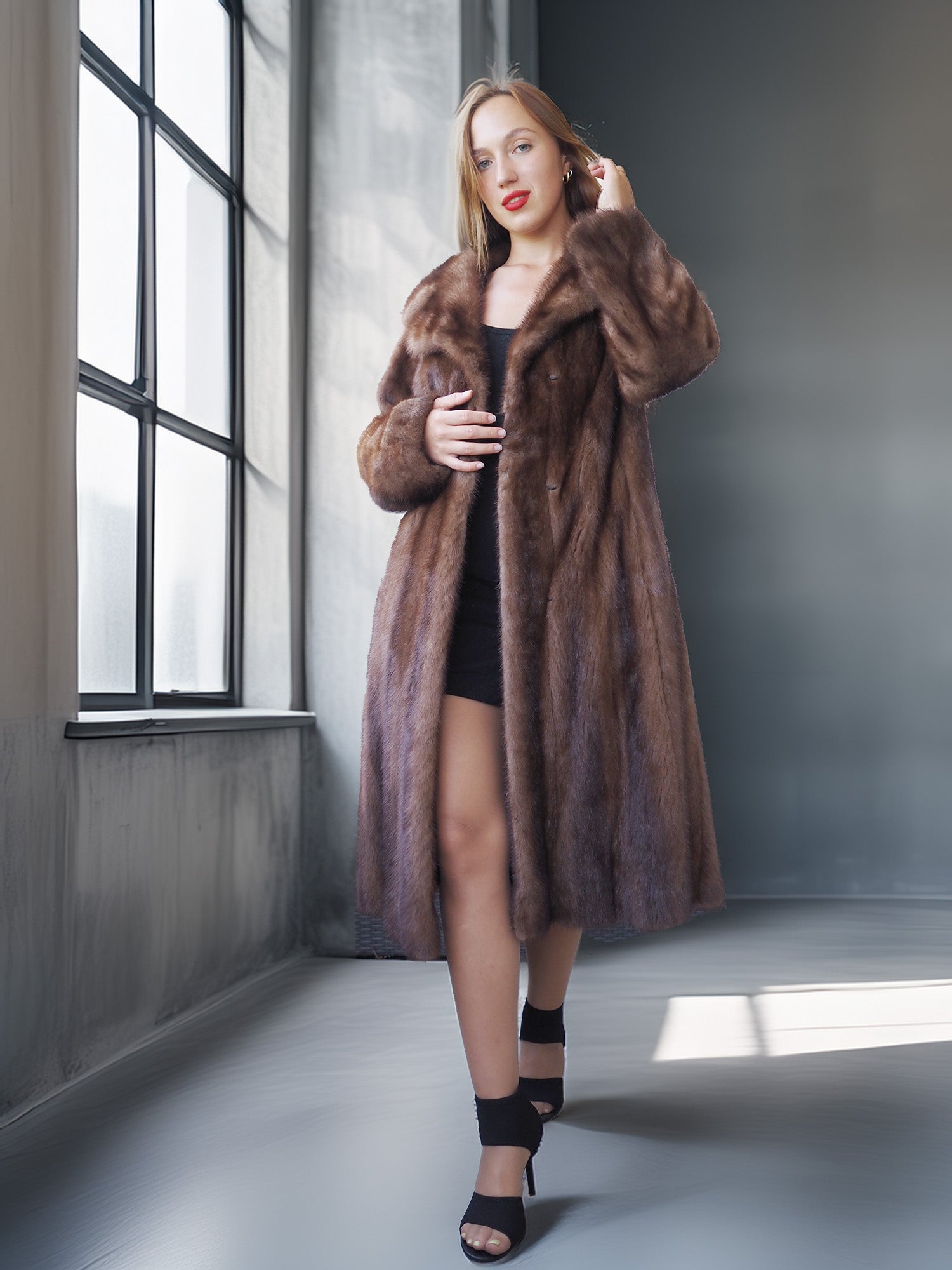Woman wearing a long brown fur coat in a modern interior setting.