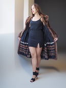 Woman wearing a long coat with fur trim against a neutral background