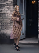 Woman wearing a fur coat standing in front of a door with a brick wall background