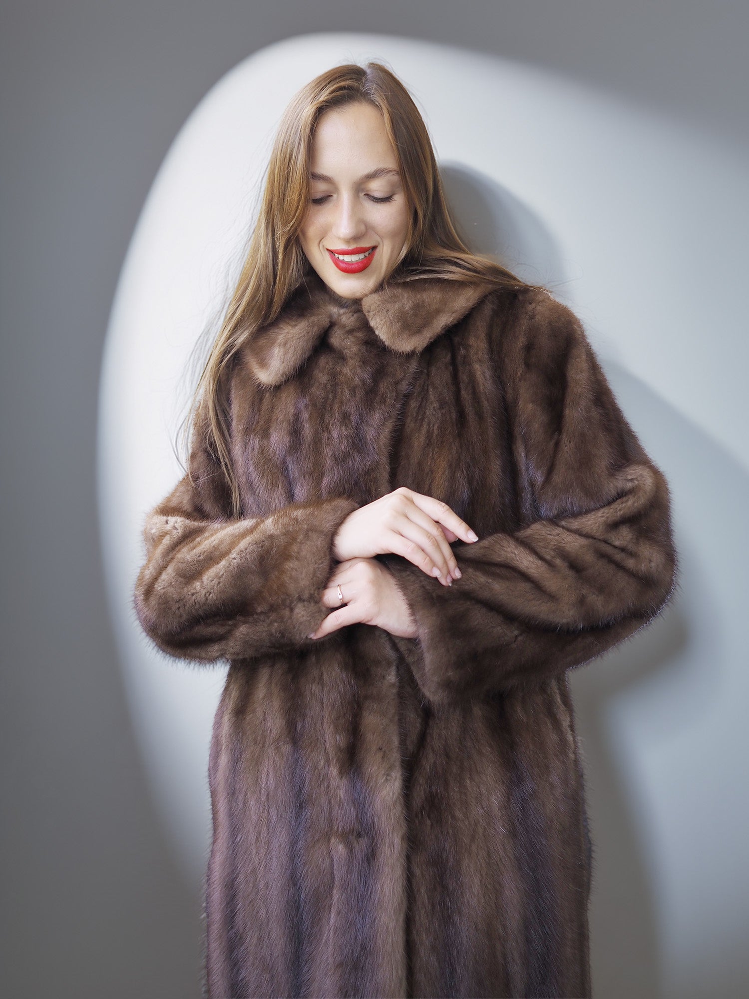 Woman wearing a brown fur coat against a plain background
