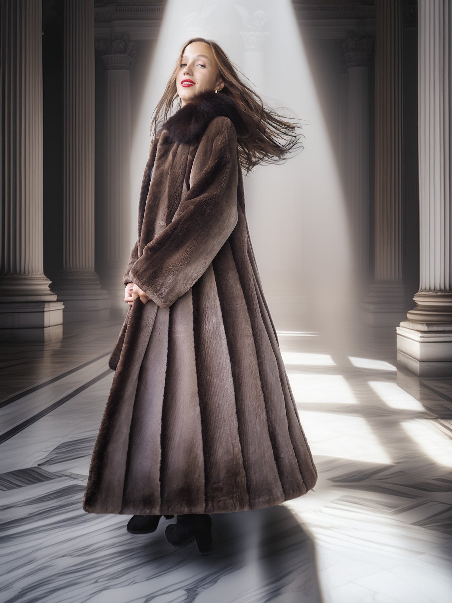 Woman in a long brown coat standing in a sunlit hallway with columns.