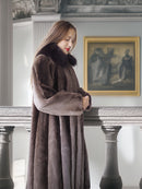 Woman wearing a long brown fur coat in an elegant interior setting.