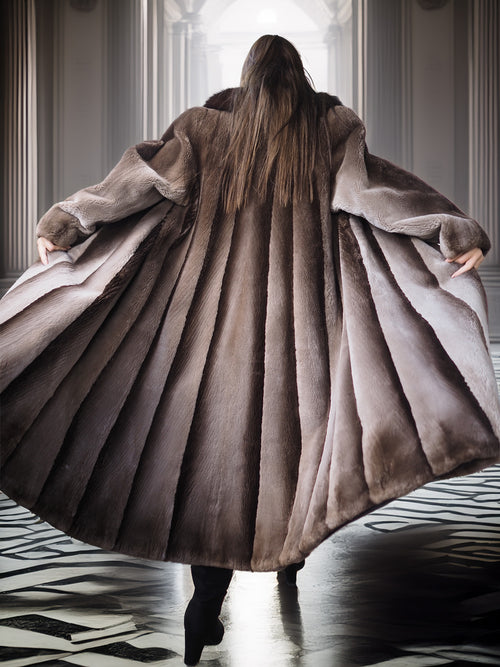 Person wearing a long fur coat in an elegant interior setting