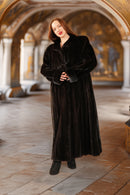 Woman wearing a long black coat in an ornate hallway