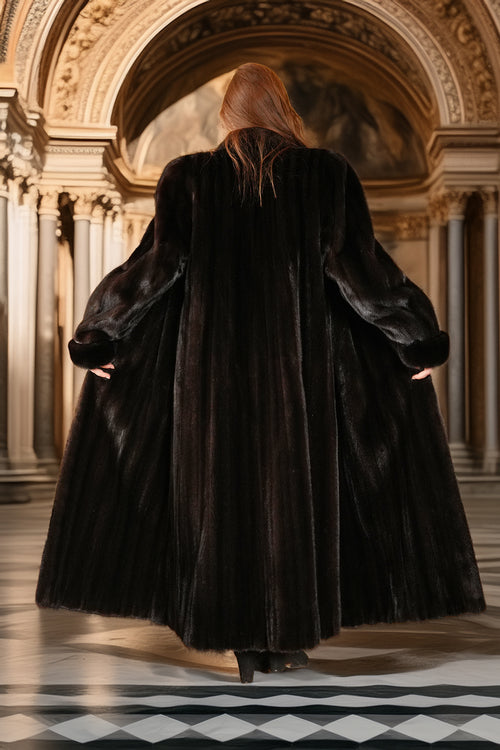 Person wearing a long black coat in an ornate hall