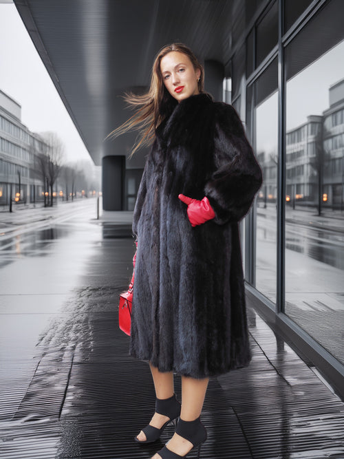 Woman in a black fur coat and red gloves standing on a wet pavement.