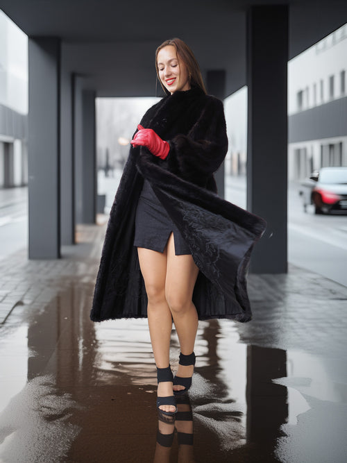 Woman in a black coat and red gloves standing on a wet street.