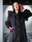 Woman wearing a black fur coat and red gloves in an indoor setting
