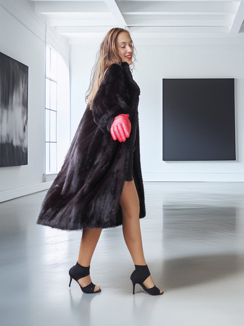 Woman wearing a black fur coat and red gloves in a modern interior setting
