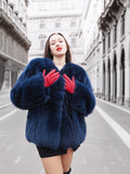 Luxury blue fox fur coat with a plush texture, styled with red gloves. A warm and elegant outerwear piece for winter fashion lovers.