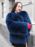 Soft and voluminous blue fox fur coat with a cozy crew neck, perfect for winter fashion. Styled with red gloves for a bold contrast.